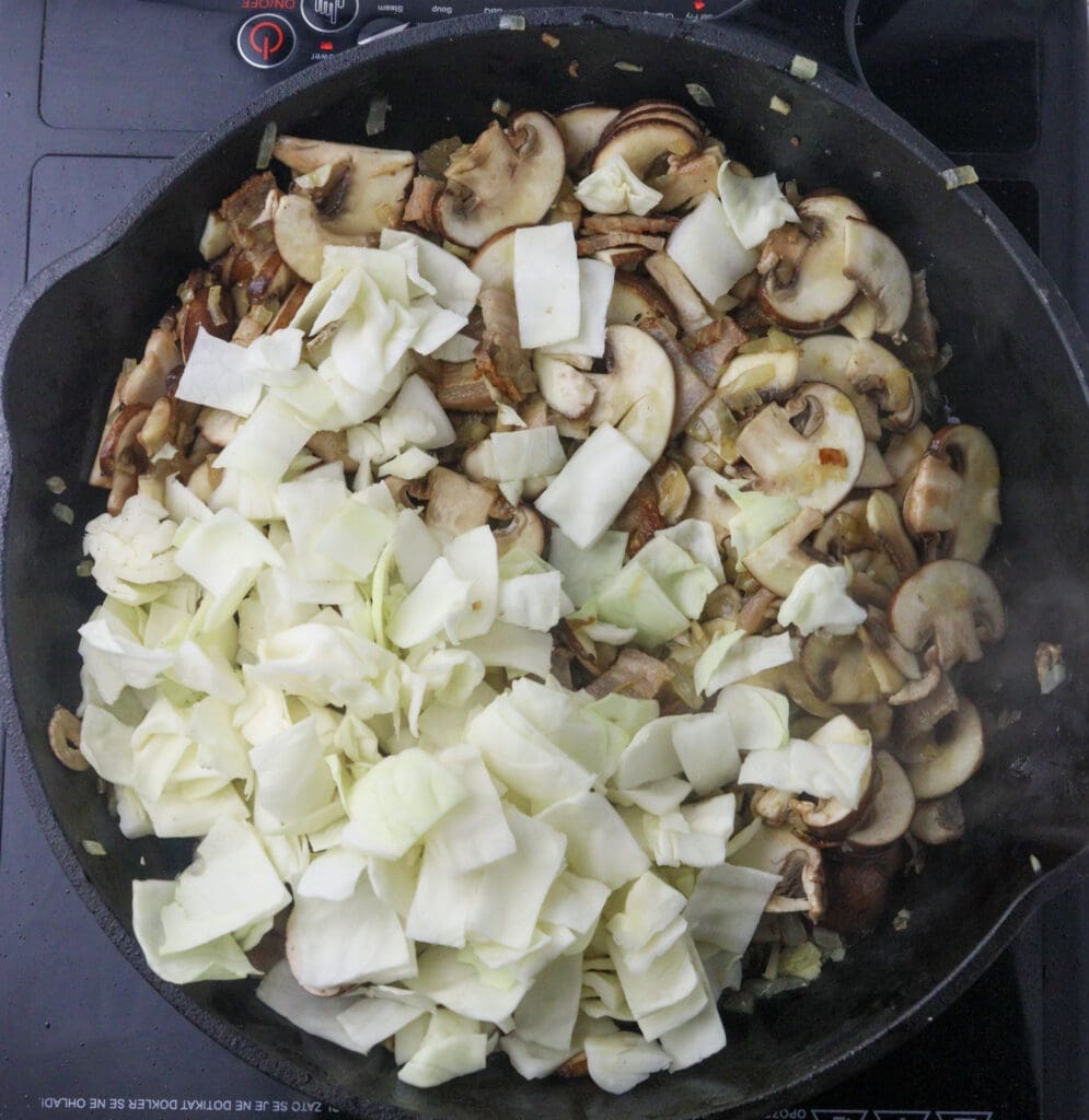 adding cabbage and mushrooms to the pan